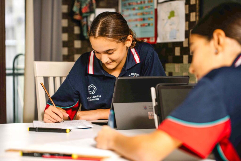 a virtual learning distance ed school student looks down at a page and writes in her book